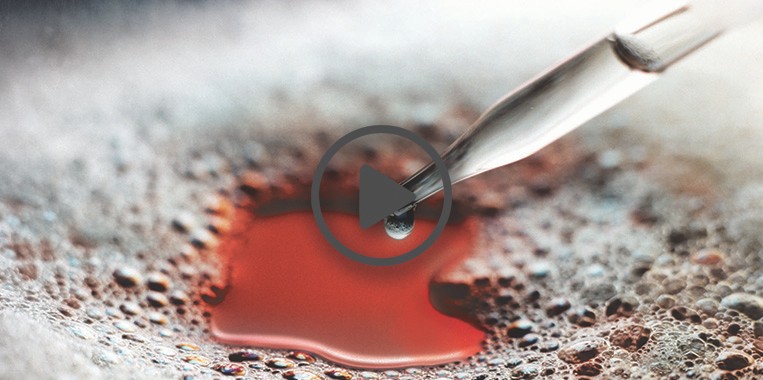 Glass eyedropper dispenses silicone antifoam into a foam covered liquid.